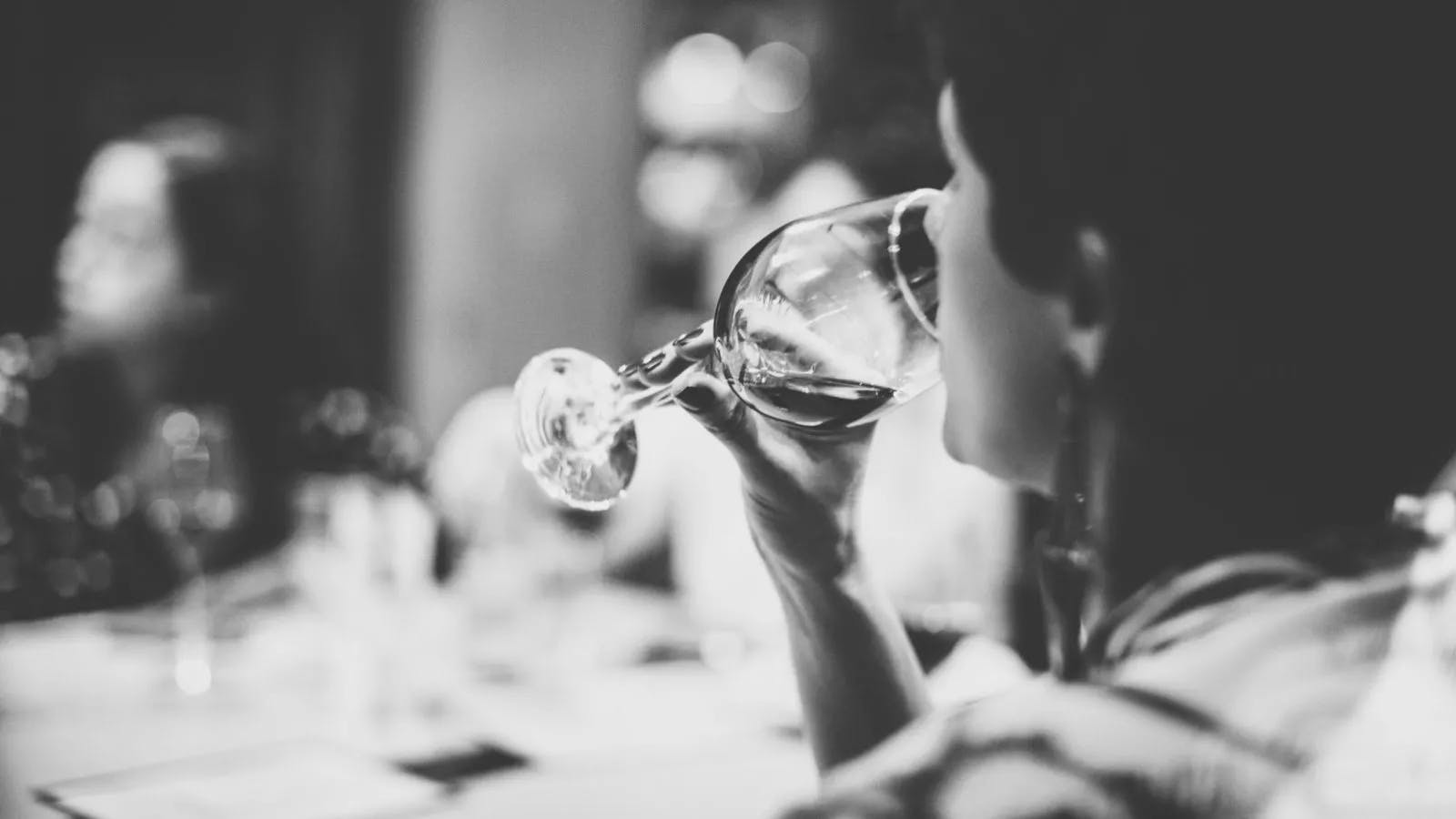 A person tasting wine, tastefully in black and white